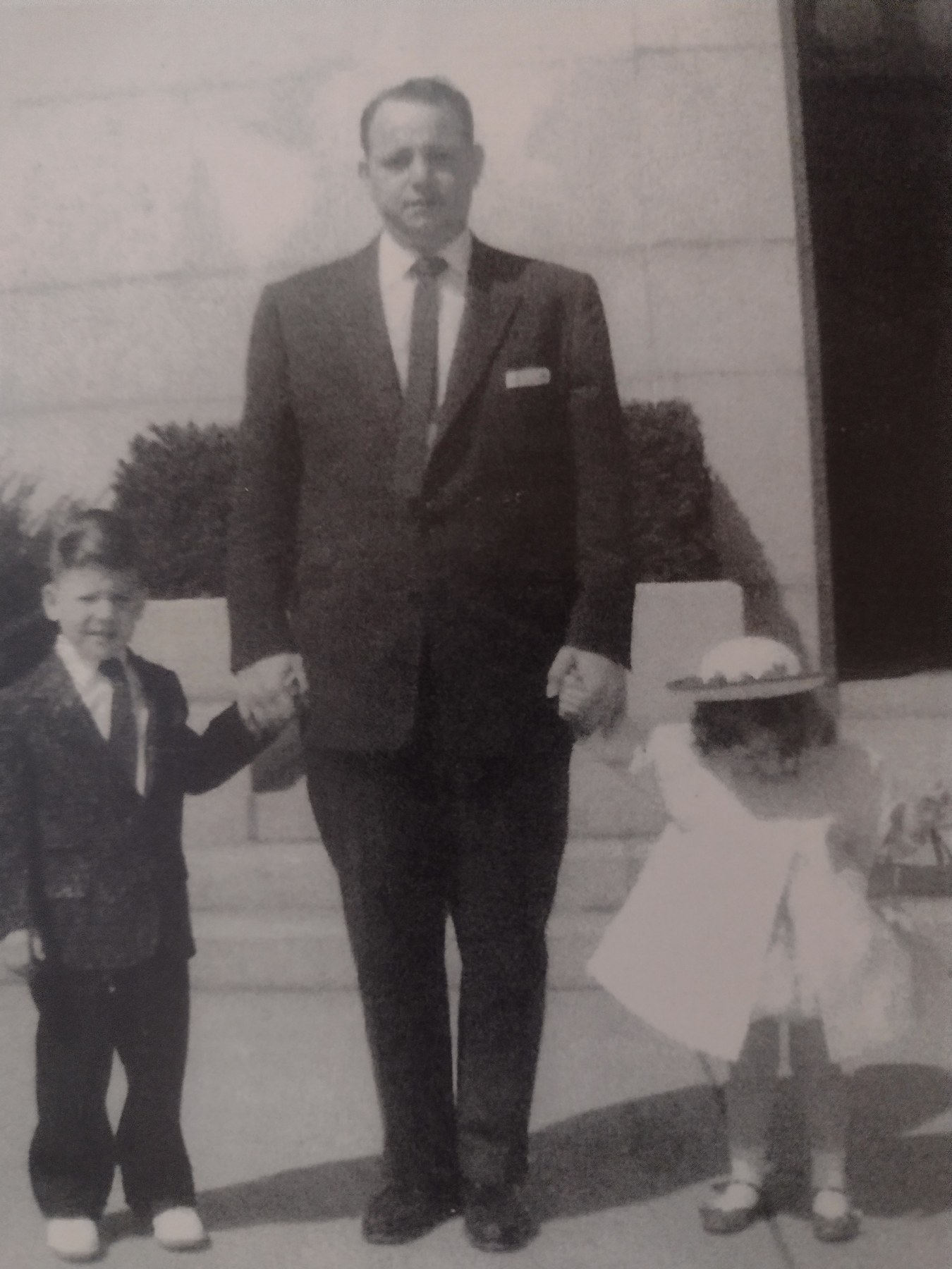 A formally dressed man standing with two children