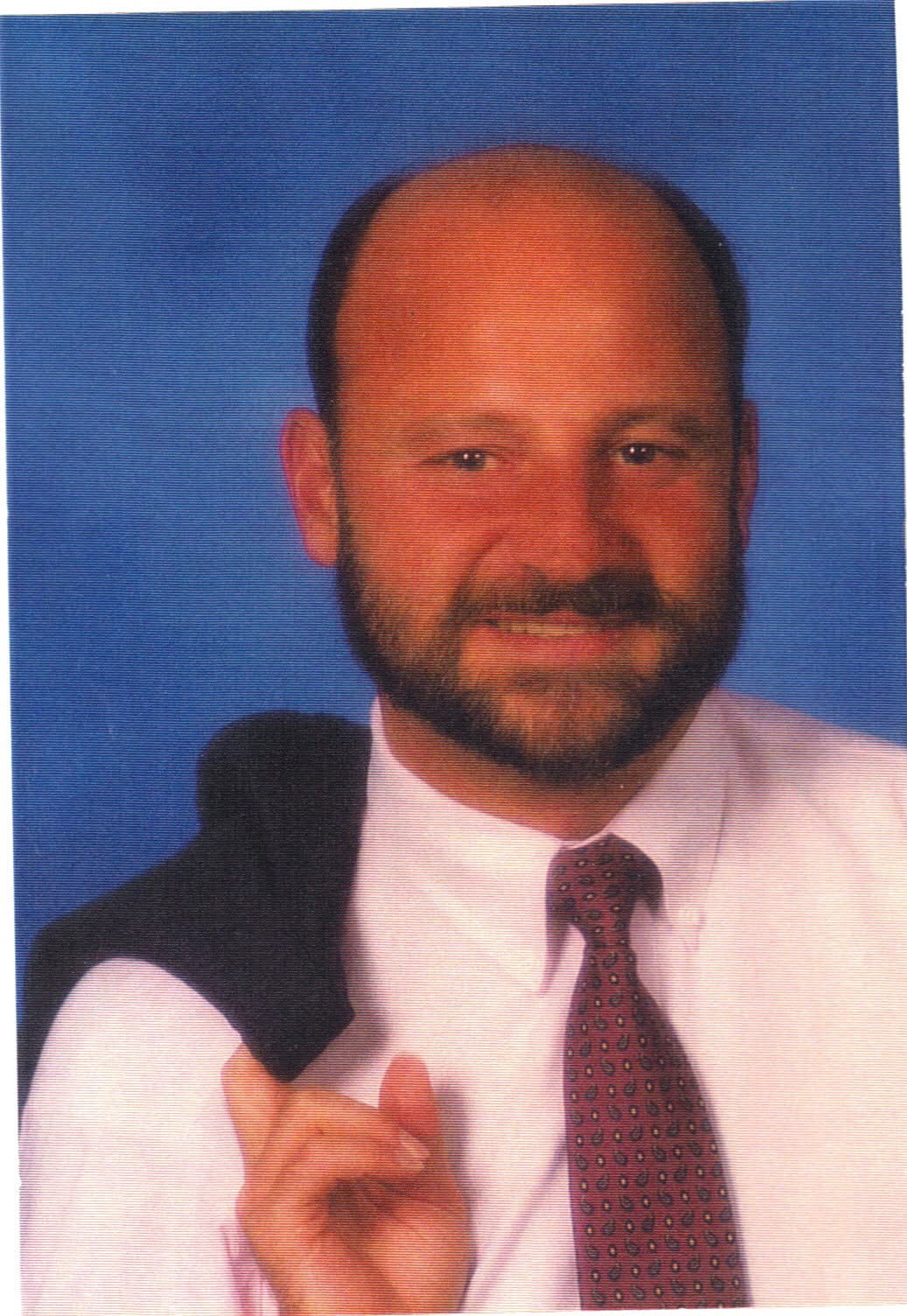 Vince wearing a shirt and tie in front of a blue background