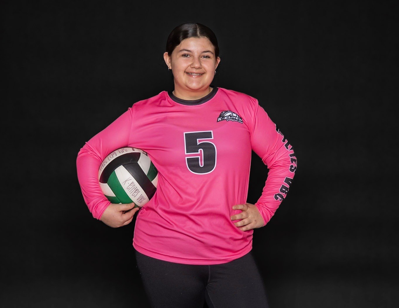 A granddaughter in a pink volleyball uniform holding a volleyball